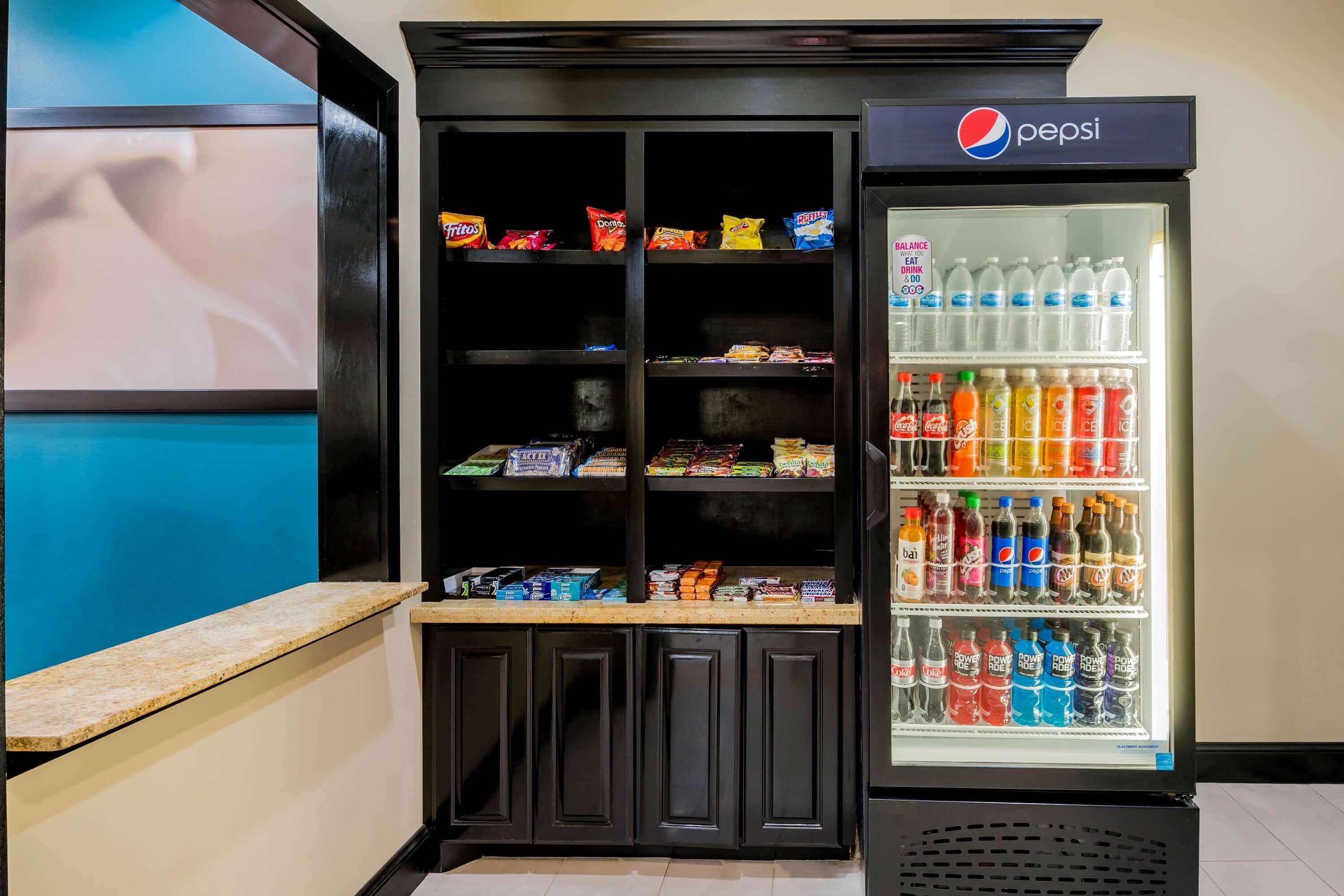 A vending machine stocked with snacks and a refrigerator with bottled water and soft drinks.
