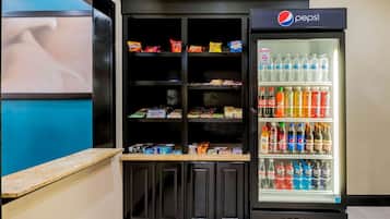A vending machine stocked with snacks and a refrigerator with bottled water and soft drinks.