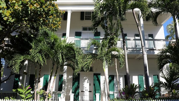 A white building with green shutters and a white picket fence.