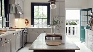A modern kitchen with white cabinetry, a central island, and a view of the outdoors.