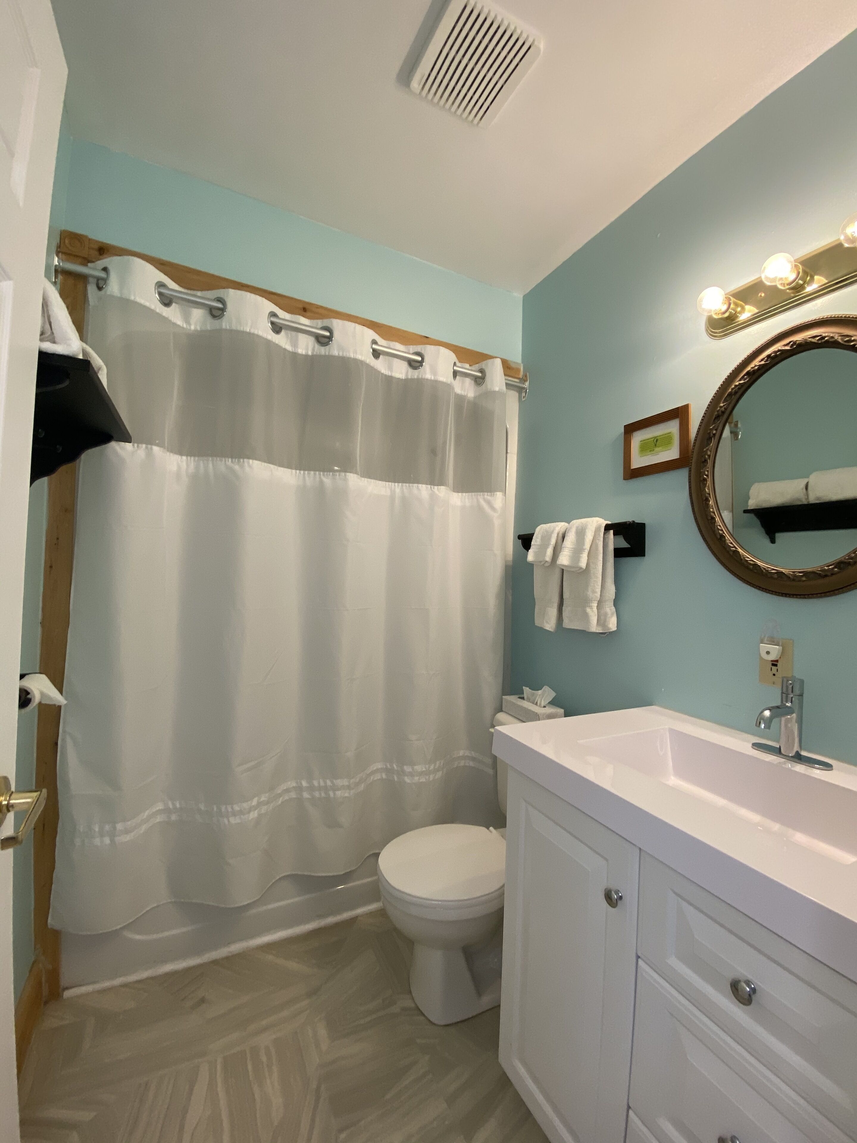 A bathroom with a white toilet, a white sink with a mirror, and a shower curtain.