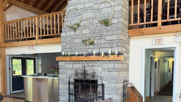 A spacious lobby with a stone fireplace, wooden beams, and a grey sofa. - Timber House Resort (Brighton)