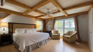 A spacious bedroom with a large bed, two chairs, a ceiling fan, and a window with curtains. - Timber House Resort (Brighton)