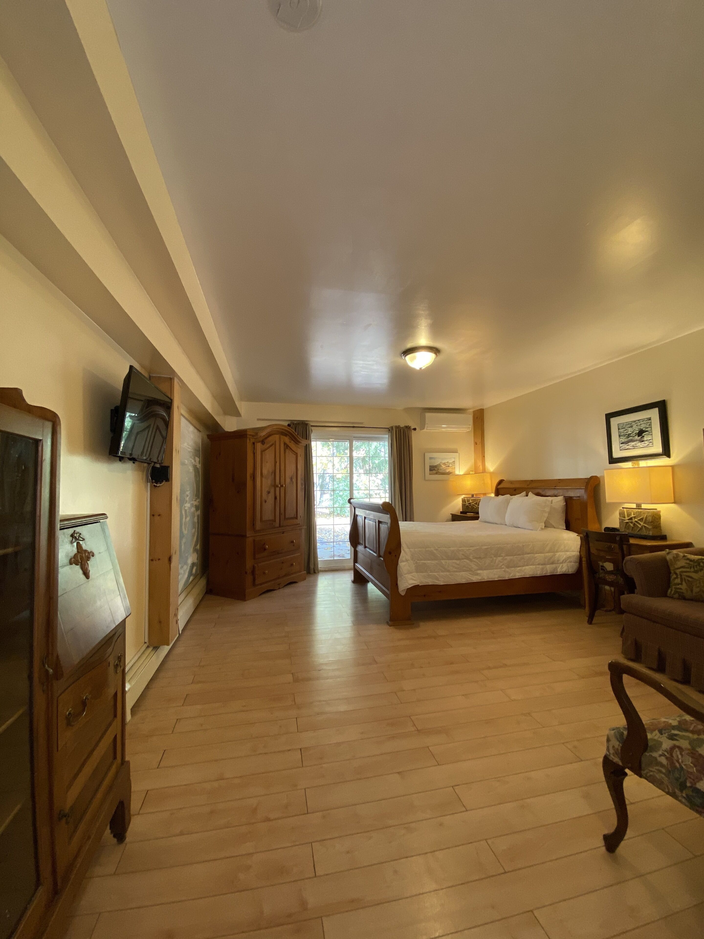 A bedroom with a wooden bed, a wooden dresser, a wooden wardrobe, and a chair.