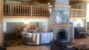 A spacious lobby with a high ceiling, wooden beams, a fireplace, and a reception desk. - Timber House Resort (Brighton)