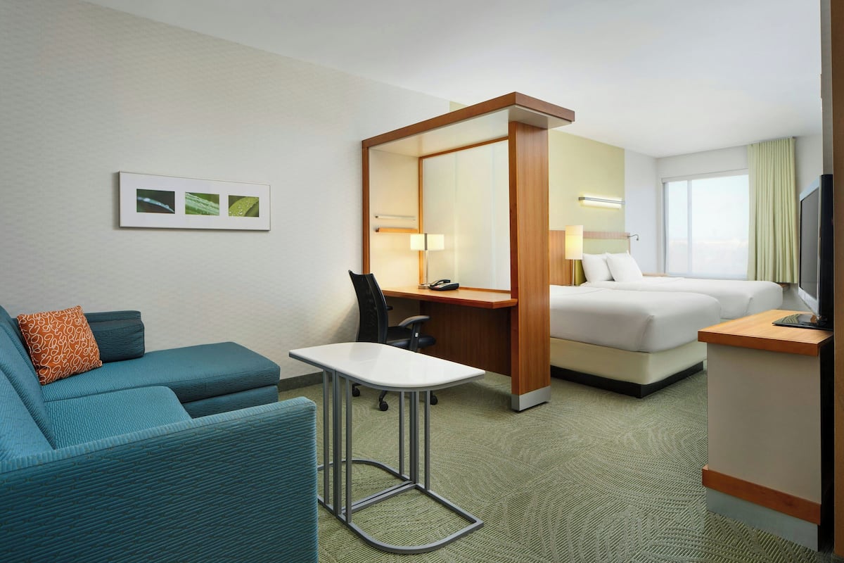 A hotel room with a sofa, a desk, a bed, and a TV.