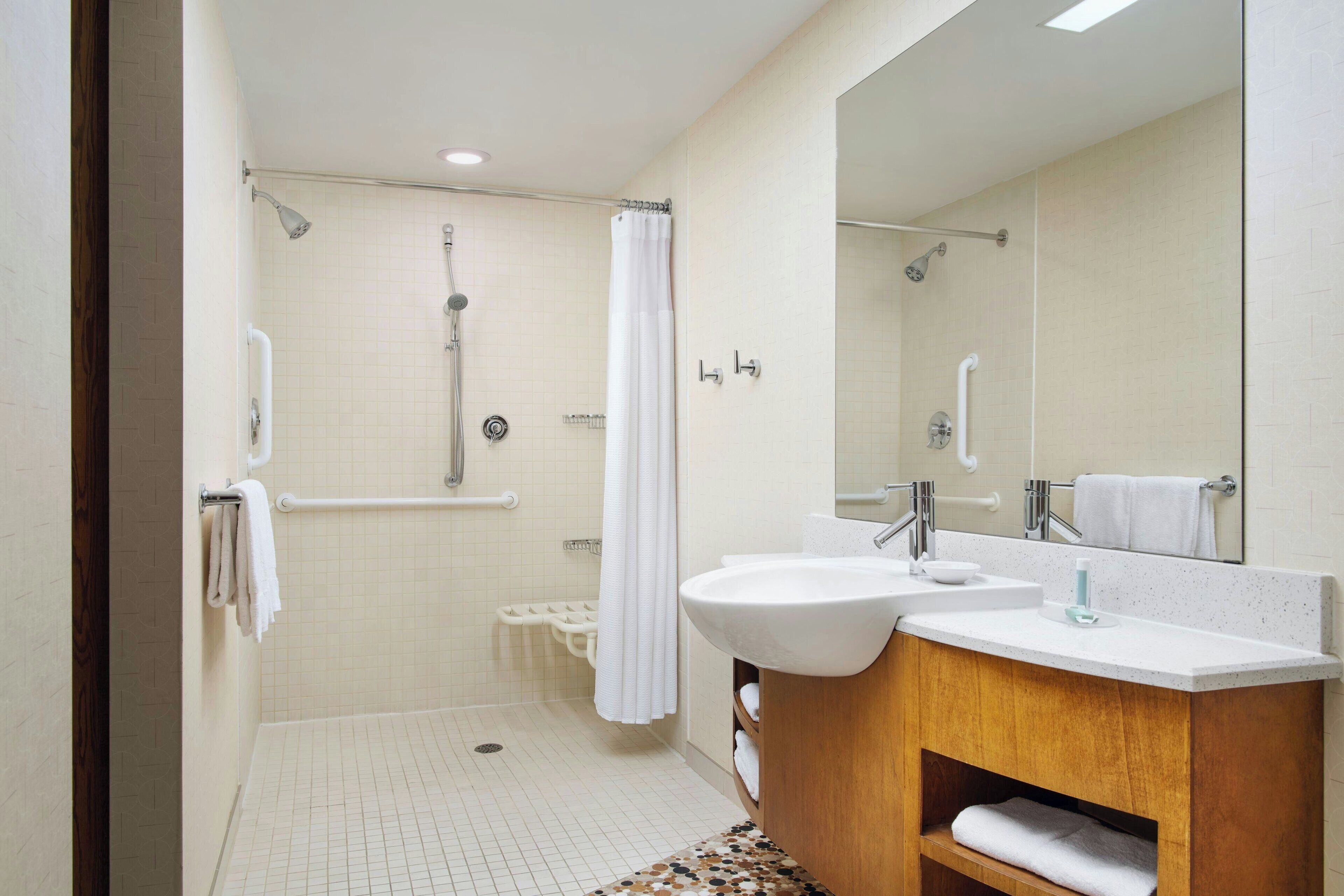 A modern bathroom with a shower, a sink, and a mirror.