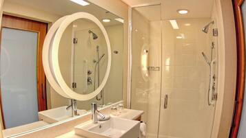 A modern bathroom with two sinks, a large mirror, and a glass-enclosed shower.
