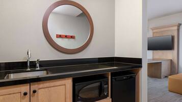 A modern kitchen with a black countertop, wooden cabinets, a built-in microwave, and a sink.