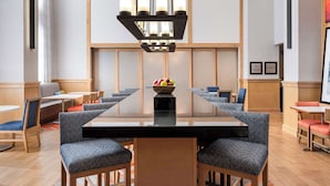 A conference room with a long table, chairs, a chandelier, and a fruit bowl.