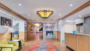 A hotel lobby with a reception desk, seating area, and a hallway leading to other rooms.