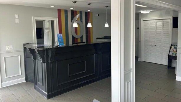 A reception area with a black counter, pendant lighting, and a colorful wall. - Studio 6 Suites Chattanooga, TN - Lookout Mtn. (Chattanooga)