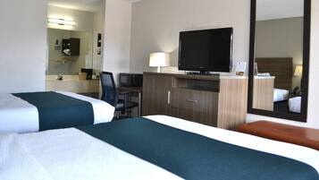 Habitación de hotel con dos camas, un escritorio con computadora, un televisor y un espejo.