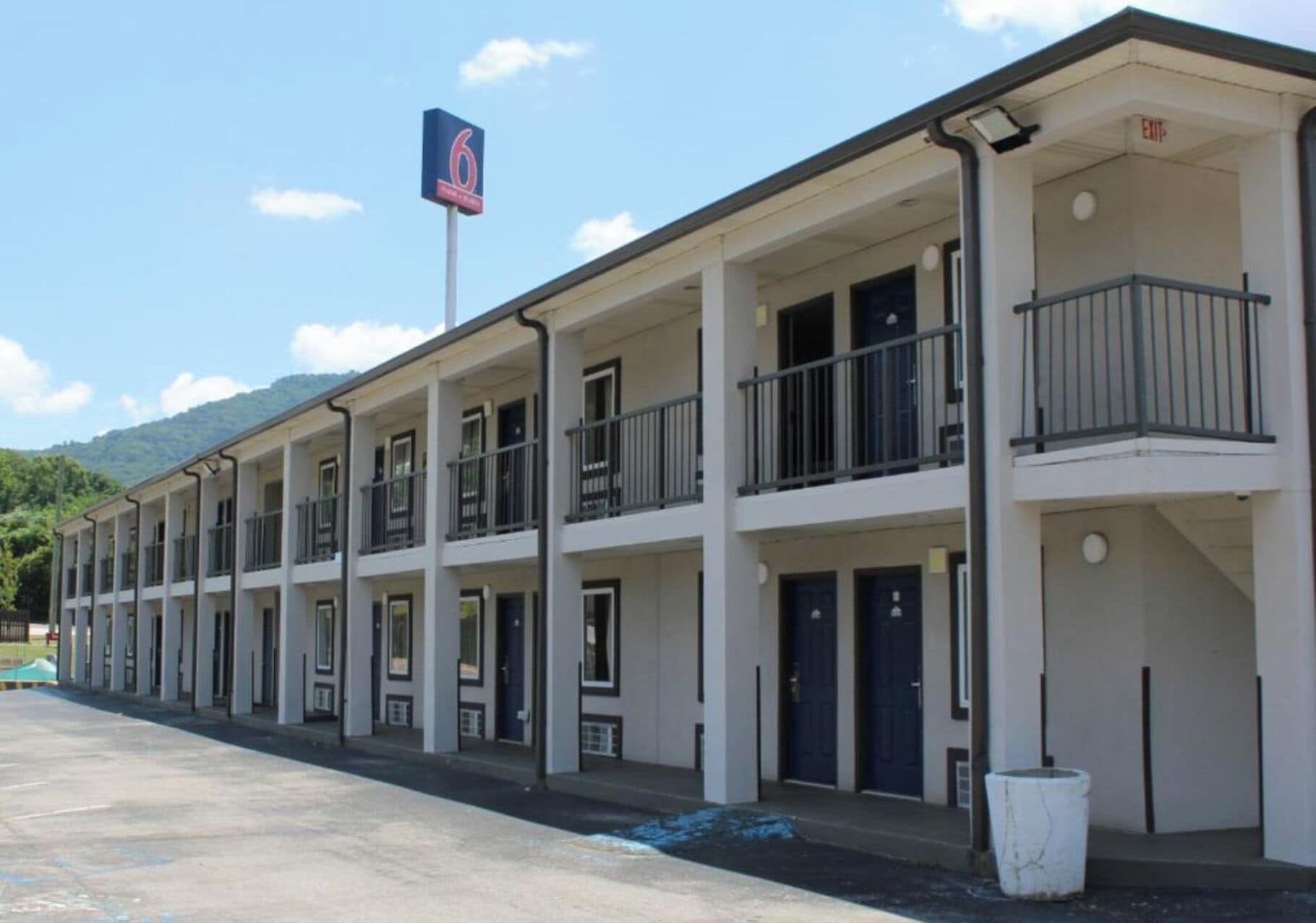 A multi-story motel with balconies, a flag, and a clear sky.