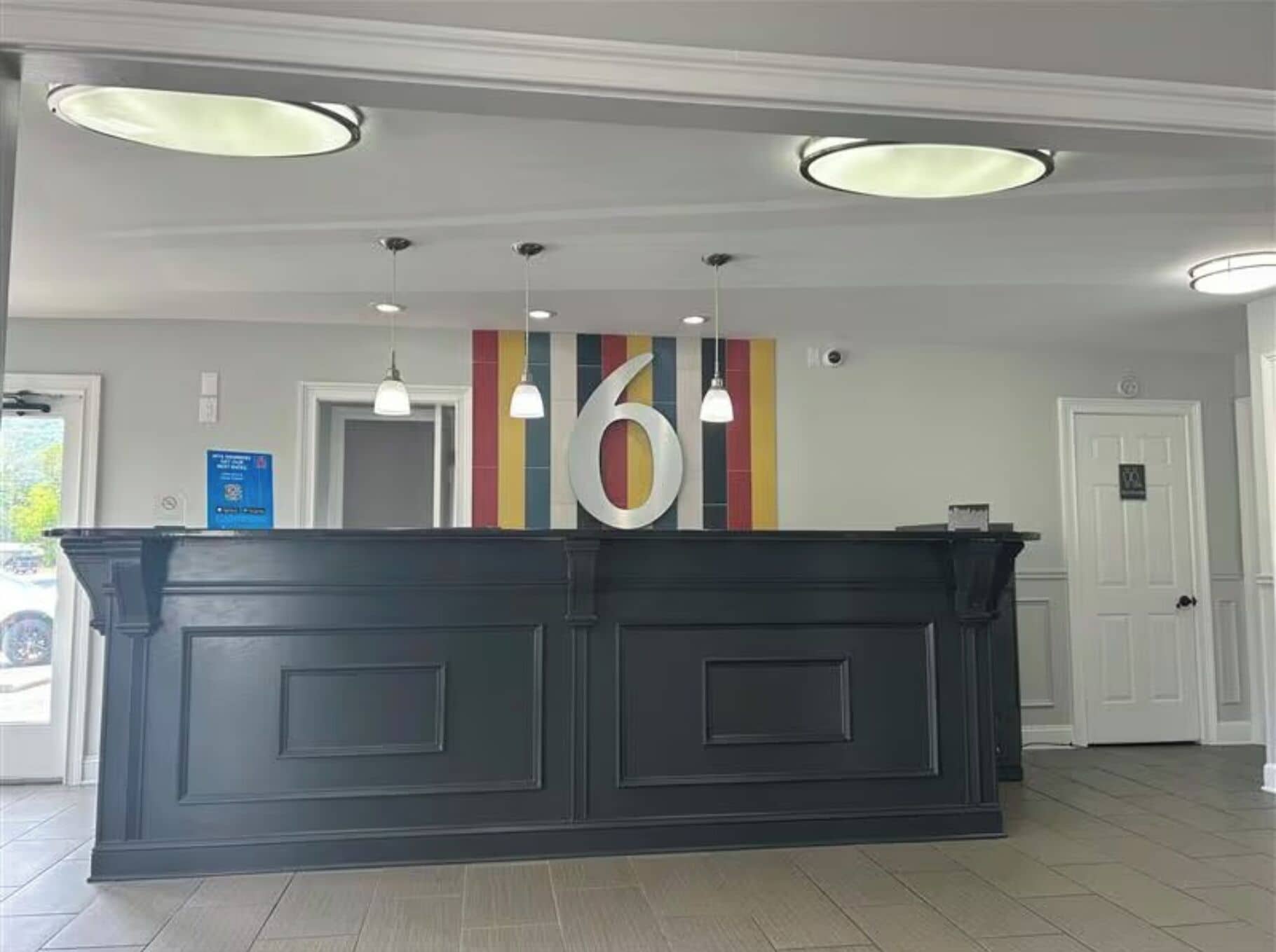 Un comptoir d’accueil avec un grand panneau portant le chiffre « 6 », des suspensions et une porte avec une enseigne.