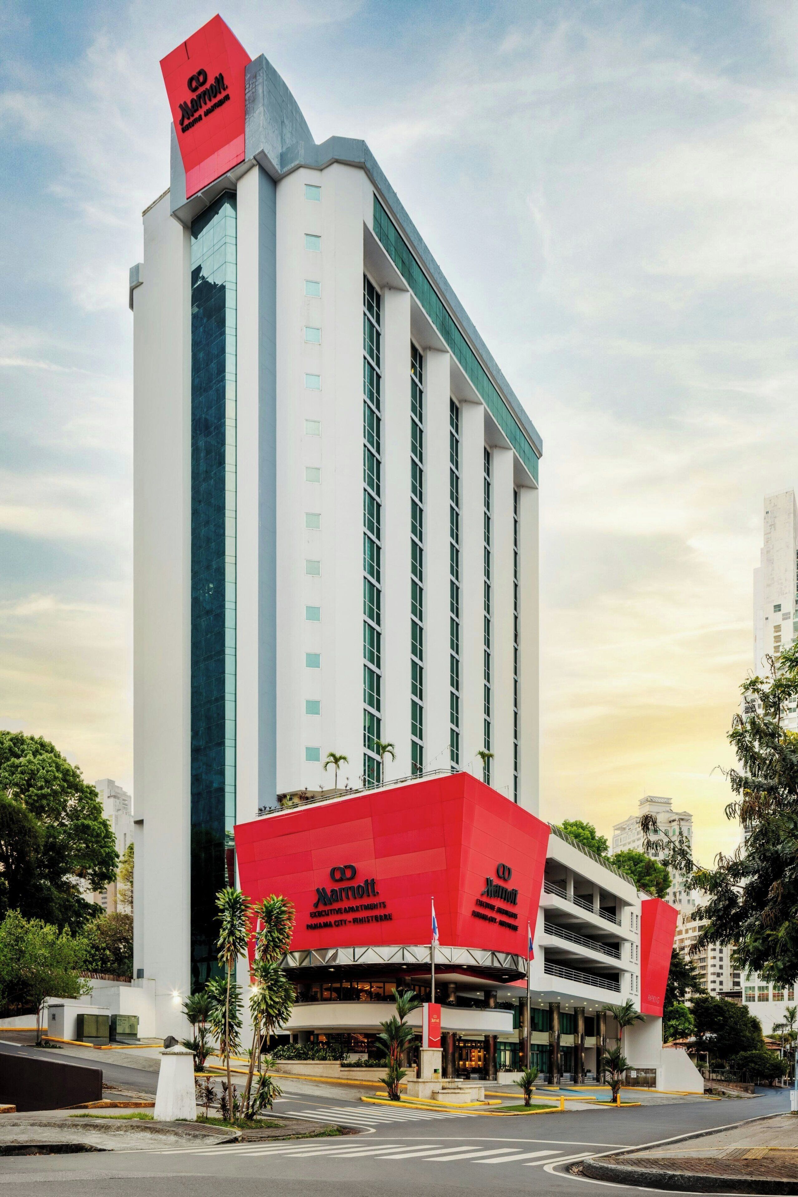 Un grand hôtel au design moderne, caractérisé par un logo rouge bien visible sur la façade et comprenant de nombreux étages.