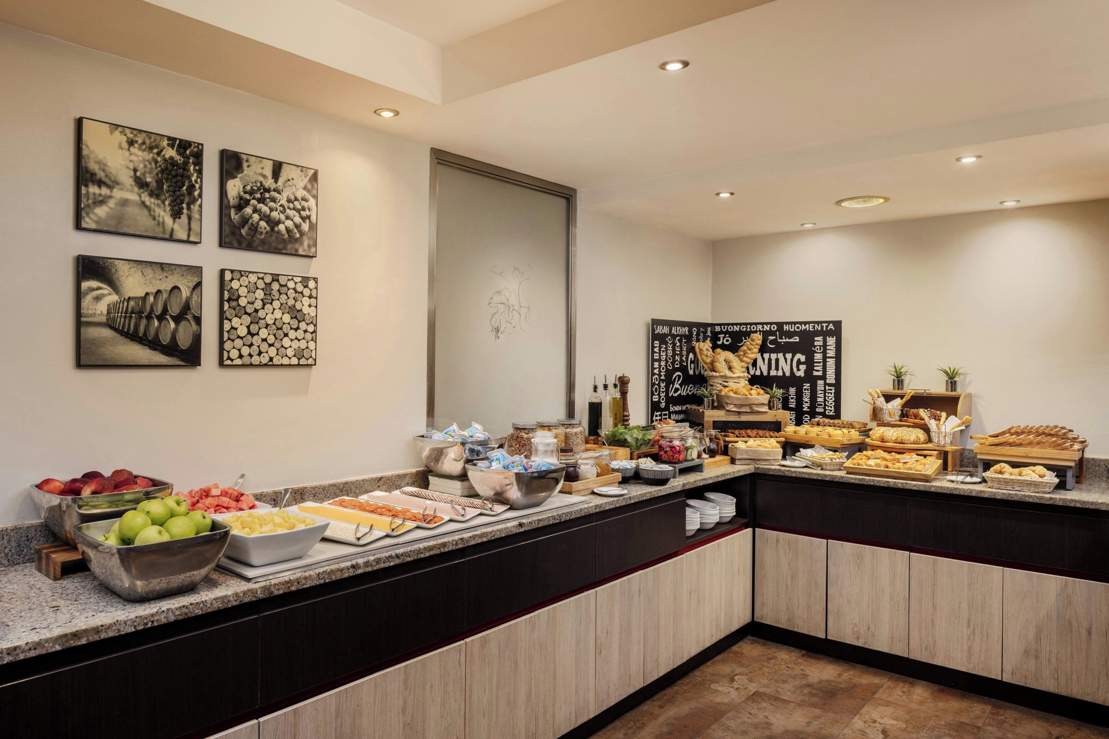 A breakfast buffet with various food items and a wall with framed pictures.