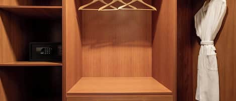 Un armario de madera con espacio para colgar, un microondas y una bata colgada a la derecha.