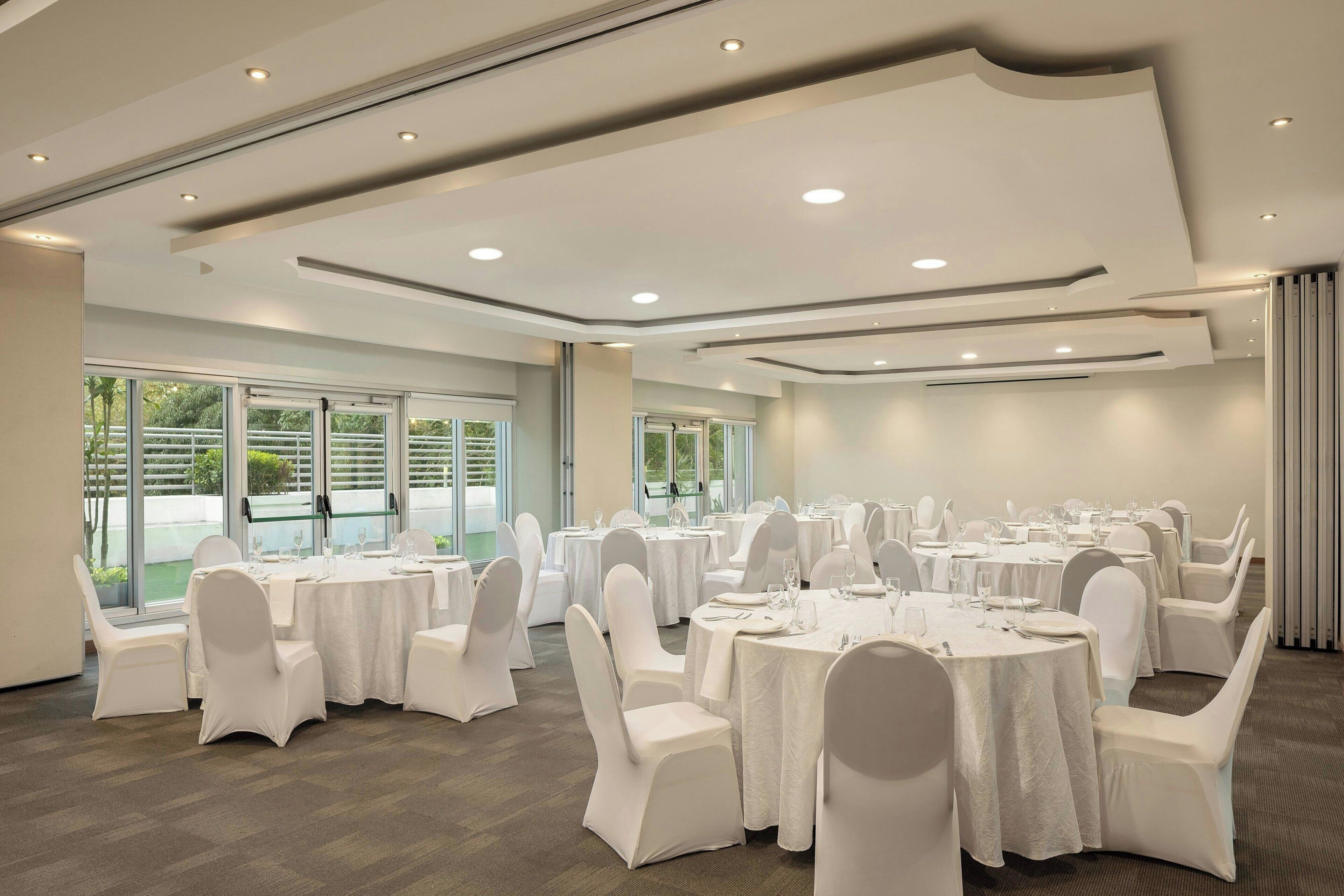 A conference room with round tables, white chairs, and large windows.