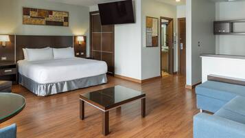 Une chambre d’hôtel équipée d’un lit, d’un bureau, d’une chaise, d’une télévision et d’une kitchenette.