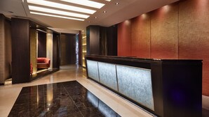 A modern hotel lobby with a reception desk, a red sofa, and a patterned wall. - The Tango Taipei Nanshi (Taipei)