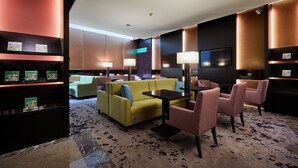 A modern hotel lobby with a yellow sofa, pink chairs, a small table, and a TV. - The Tango Taipei Nanshi (Taipei)