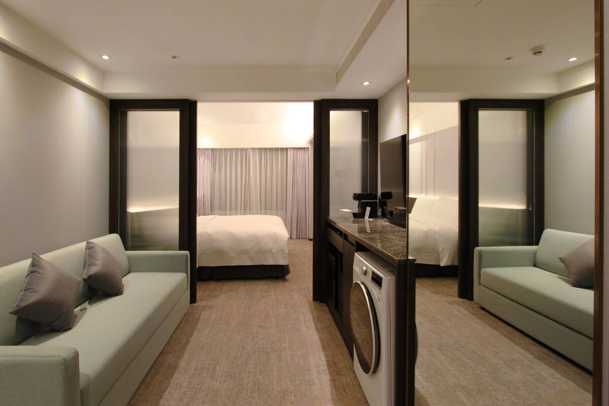 Ein Hotelzimmer mit einem Bett, einer Couch, einem Schreibtisch mit Waschmaschine und einem Spiegel.