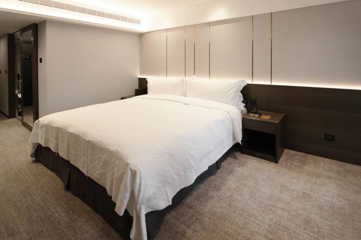 Ein modernes Hotelzimmer mit einem großen Bett, einem Nachttisch und einem Beistelltisch.