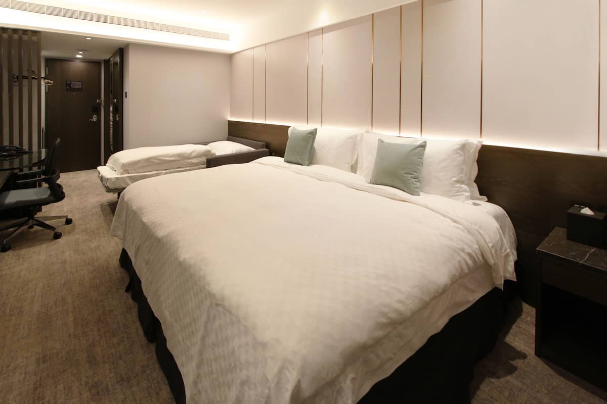 Ein Hotelzimmer mit zwei Betten, einem Schreibtisch und einem Stuhl.