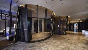 Eine großzügige Lobby mit geschwungenem Design, ein Marmorboden und moderne Beleuchtung.