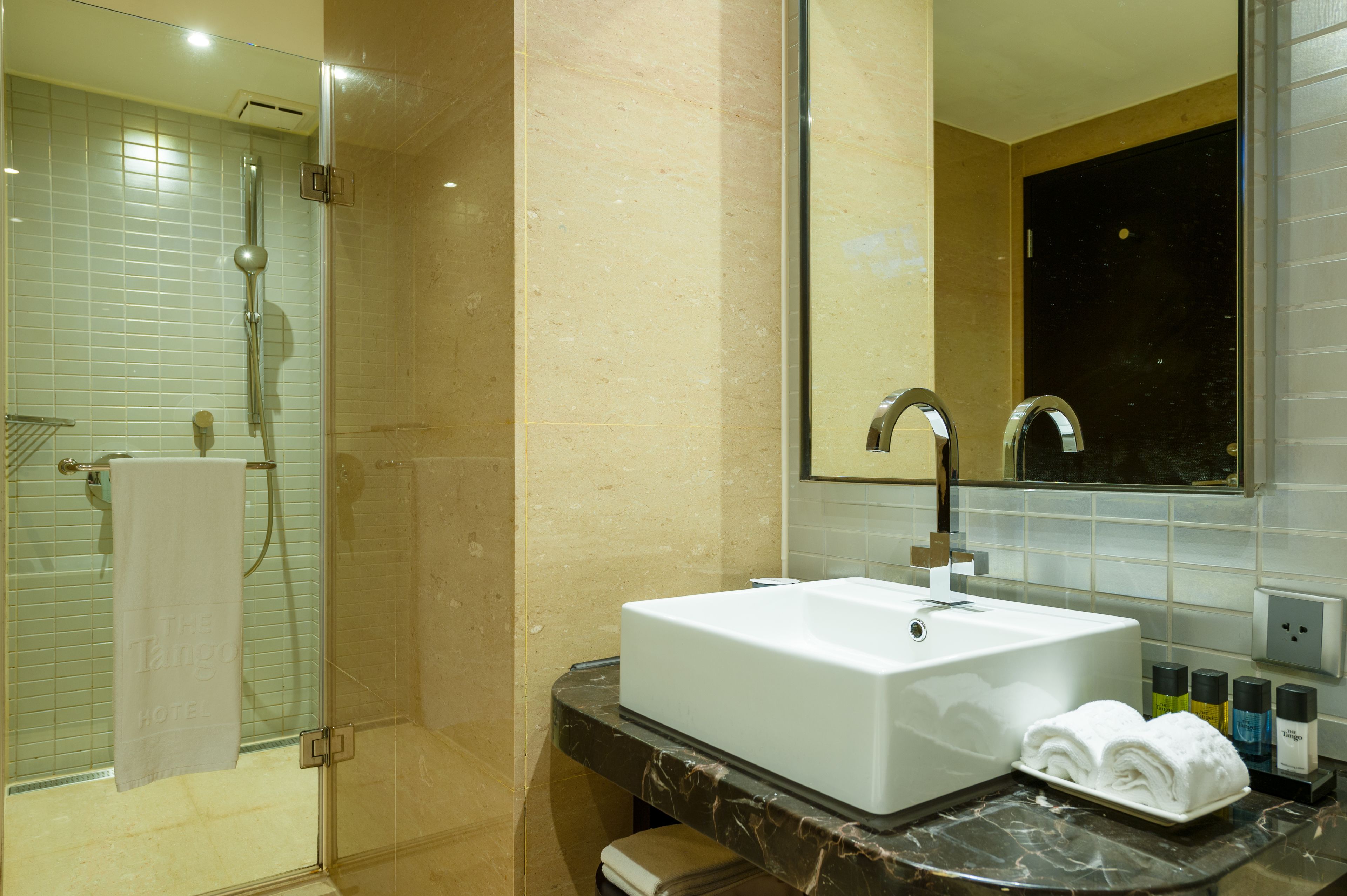 A modern bathroom with a glass-enclosed shower, a white sink, and a large mirror.