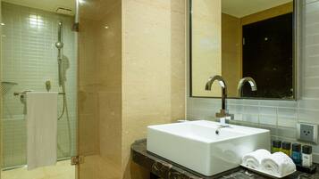 A modern bathroom with a glass-enclosed shower, a white sink, and a large mirror.
