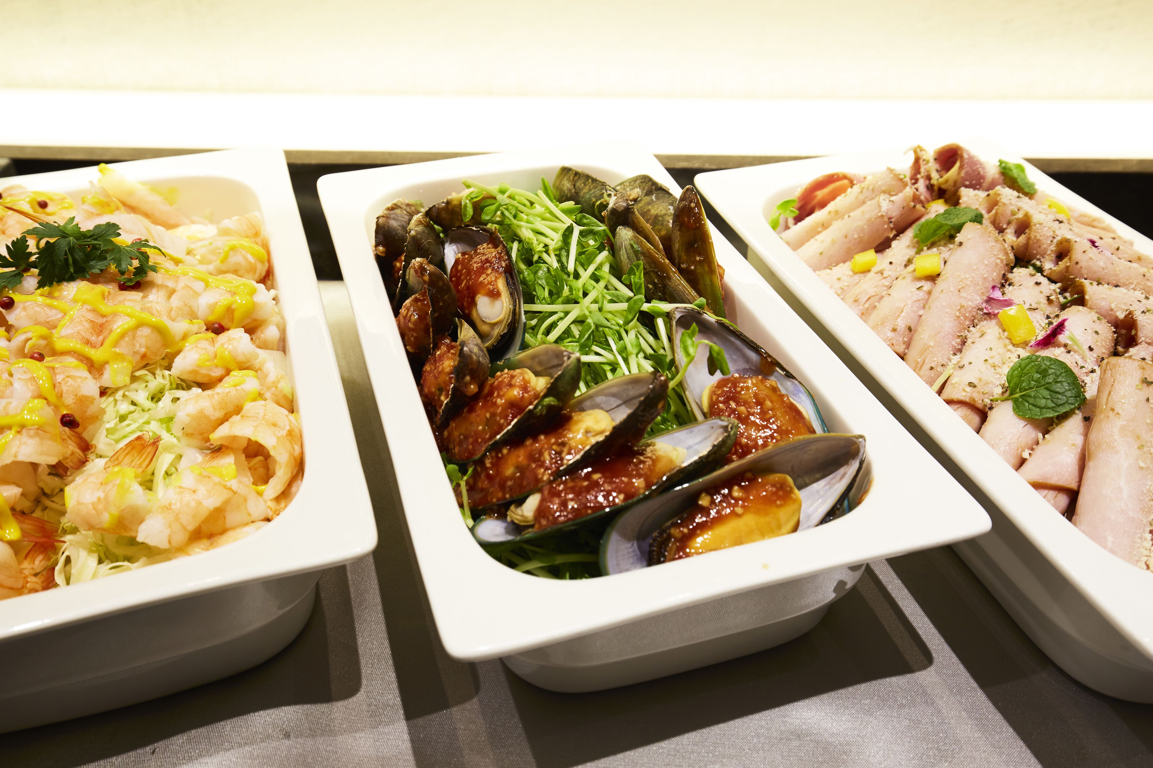 Three rectangular dishes containing seafood.