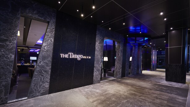 Eine moderne Hotellobby mit einem Marmor-Rezeptionsschalter und einem Schild mit der Aufschrift "The Tango".