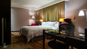 Una habitación de hotel con una cama, un escritorio, una silla y dos lámparas.