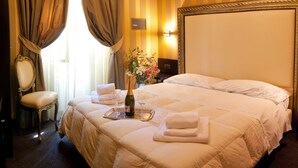 A hotel room with a large bed, a bedside table, a chair, a mirror, and a window with curtains. - Domus RomAntica (Rome)