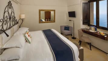 A hotel room with a bed, a desk, a chair, a TV, and a window with a view.