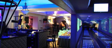 A modern bar area with a bar counter, stools, and a buffet table.