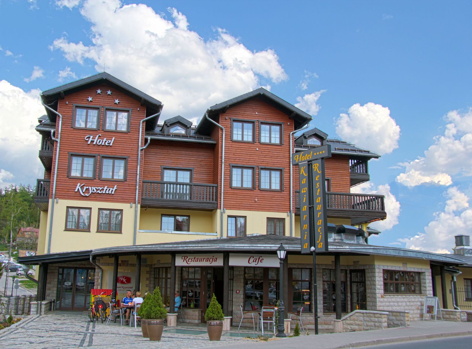 Hotel con restaurante y cafetería en la planta baja, con fachada de madera y balcones.