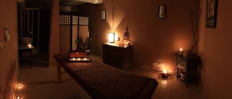Una habitación tenuemente iluminada con un largo banco de madera, un pequeño altar con velas y una tradicional pantalla japonesa shoji.