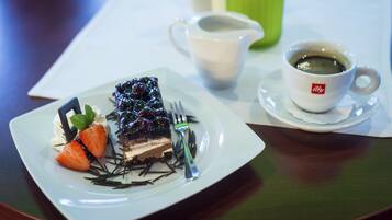 A dessert plate with a slice of cake, strawberries, and a fork on a table.