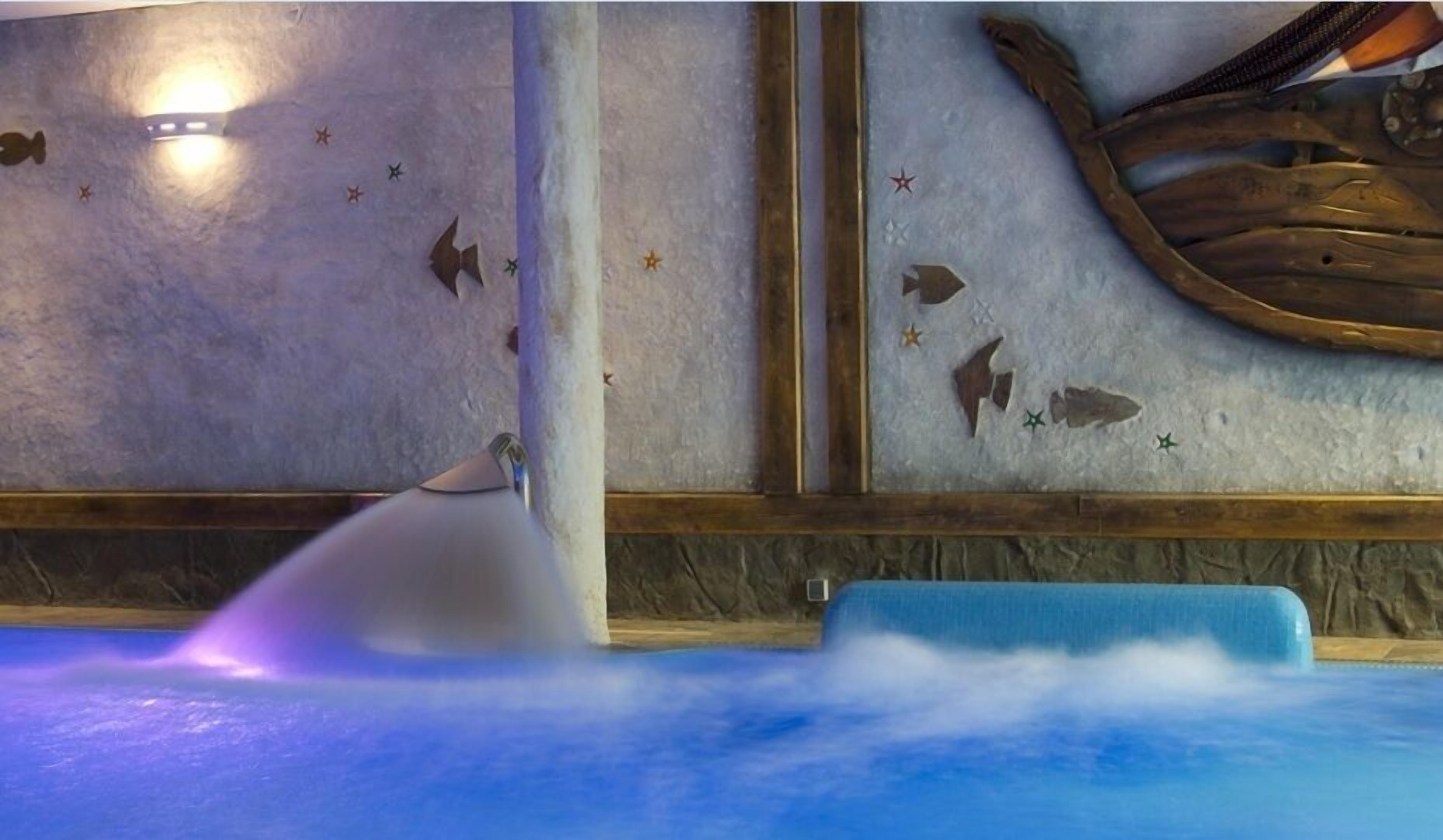 A spa area with a hot tub, a wooden wall with star decorations, and a stone wall.