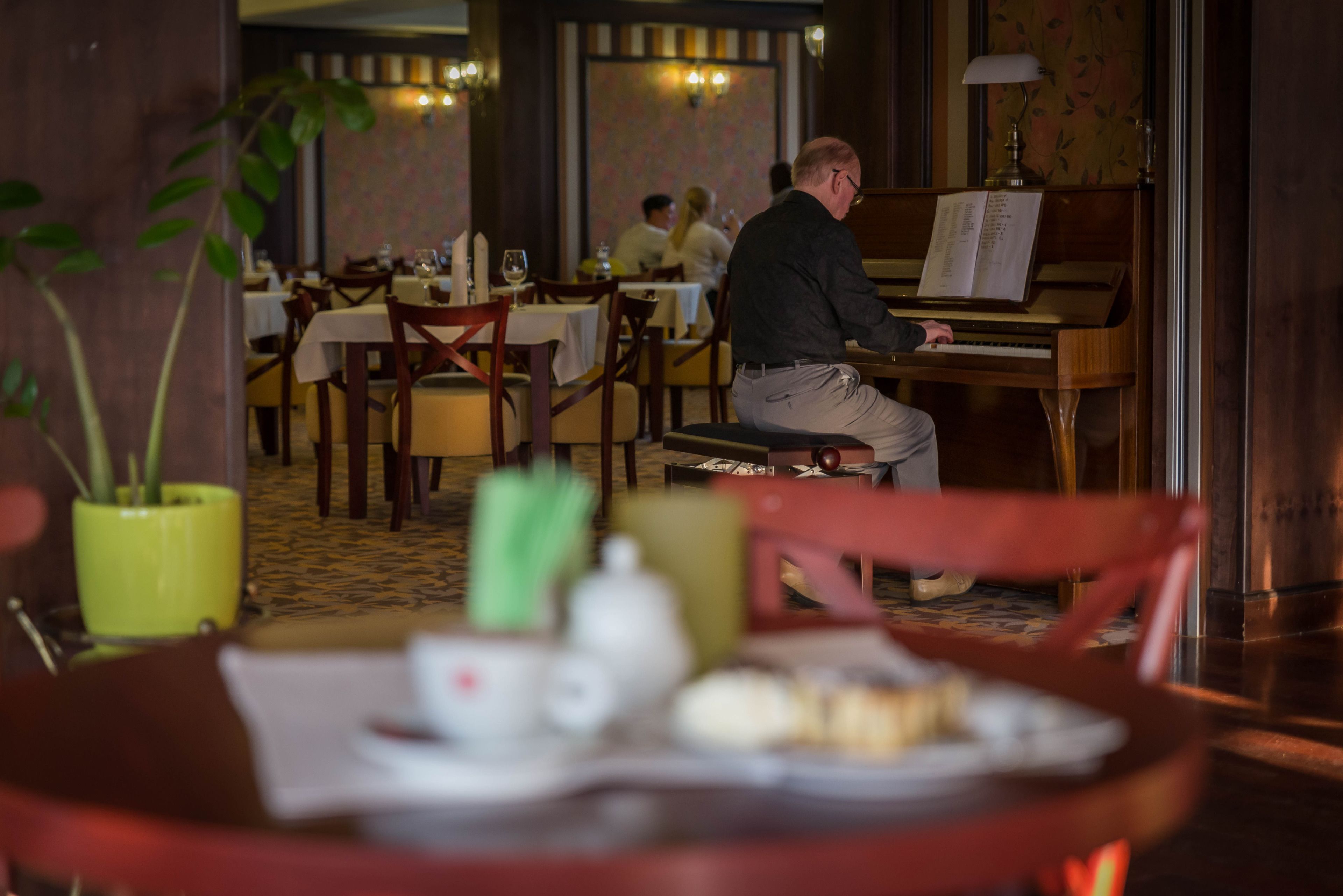 A restaurant with a piano, tables, chairs, and a dining area.