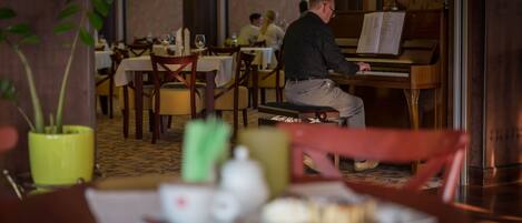A restaurant with a piano, tables, chairs, and a dining area.