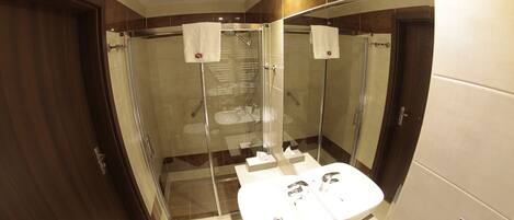 A modern bathroom with a glass-enclosed shower, a large mirror, and a vanity with a sink and countertop.
