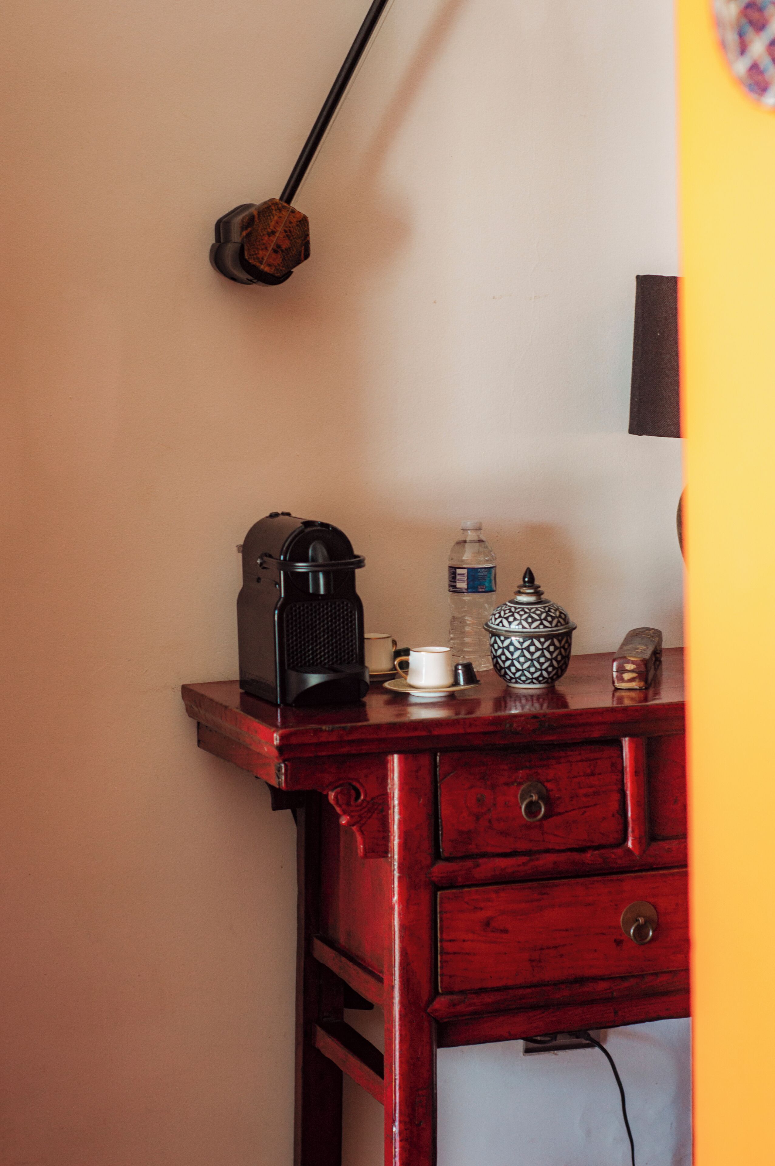 Un escritorio de madera con una cafetera, una botella de agua, un hervidor de té y un teléfono.