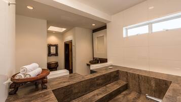 Un baño moderno con una bañera grande, una bandeja de madera con toallas y un lavabo con espejo.