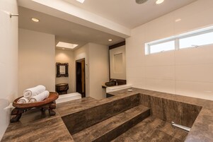 Un baño moderno con una bañera grande, una bandeja de madera con toallas y un lavabo con espejo.