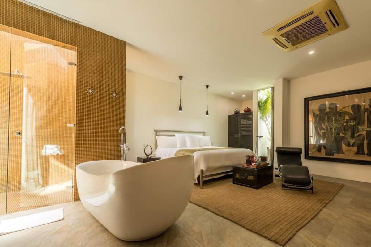 Een moderne slaapkamer met een groot bed, een witte badkuip en een kunstwerk in een lijst aan de muur.