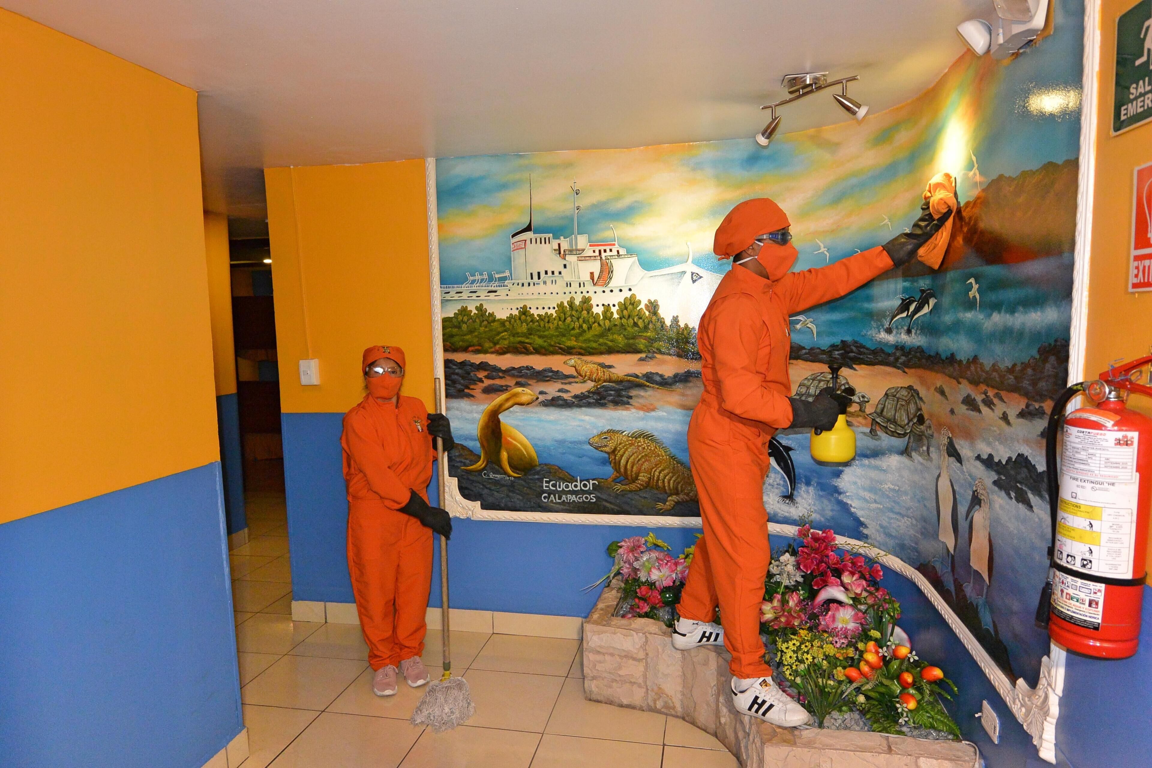 A mural with a ship and animals, a fire extinguisher, and a person in orange cleaning.